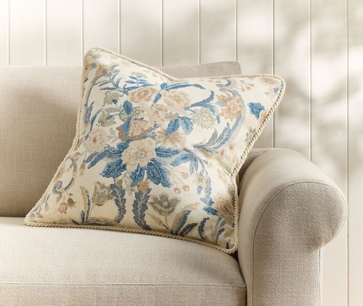 Floral blue and beige pillow on a light upholstered armchair.