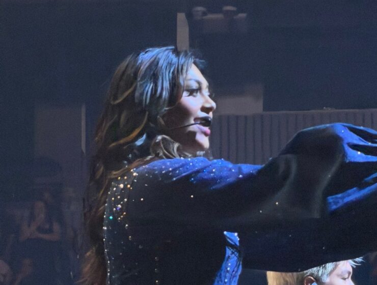 A Worlds Collide performer singing in a sparkling blue costume at Chase Center.