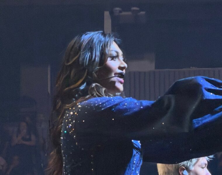 A Worlds Collide performer singing in a sparkling blue costume at Chase Center.