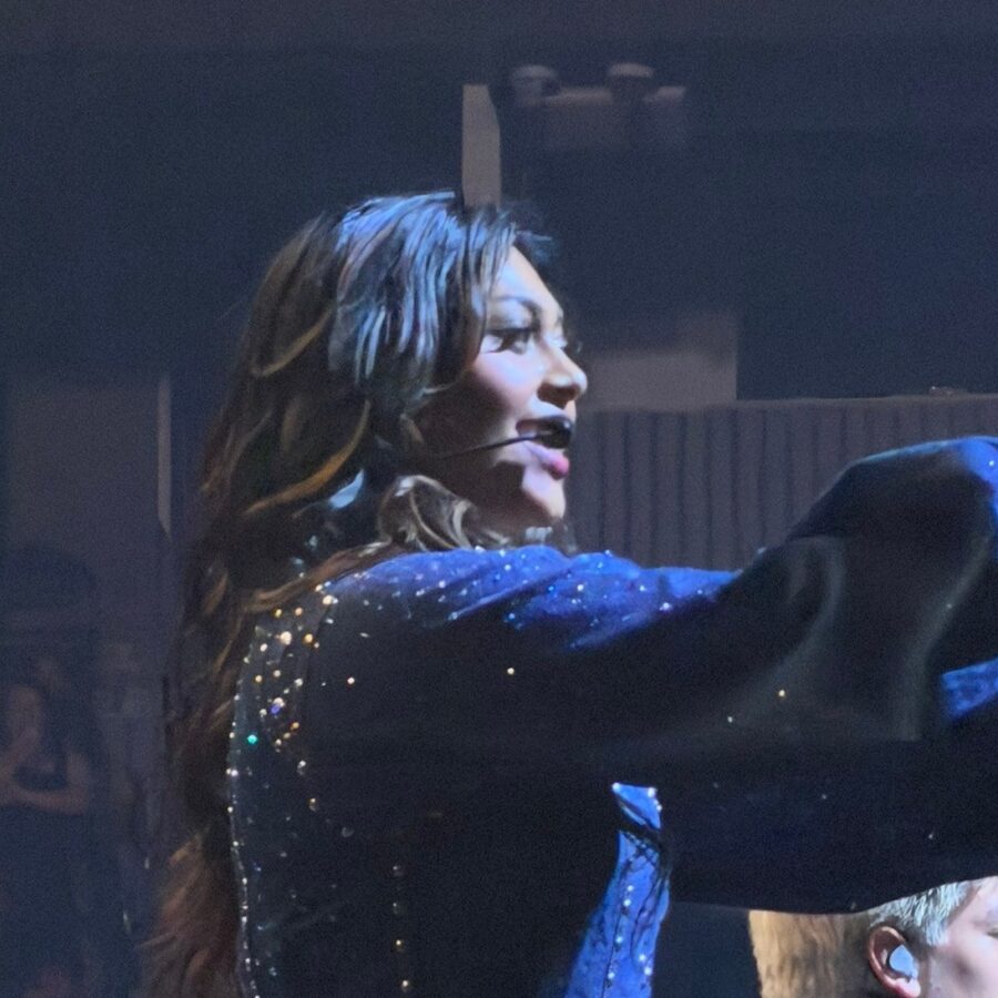 A Worlds Collide performer singing in a sparkling blue costume at Chase Center.