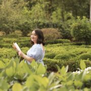 Jocelyne Roman holding a book in a green garden