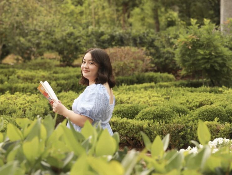 Jocelyne Roman holding a book in a green garden