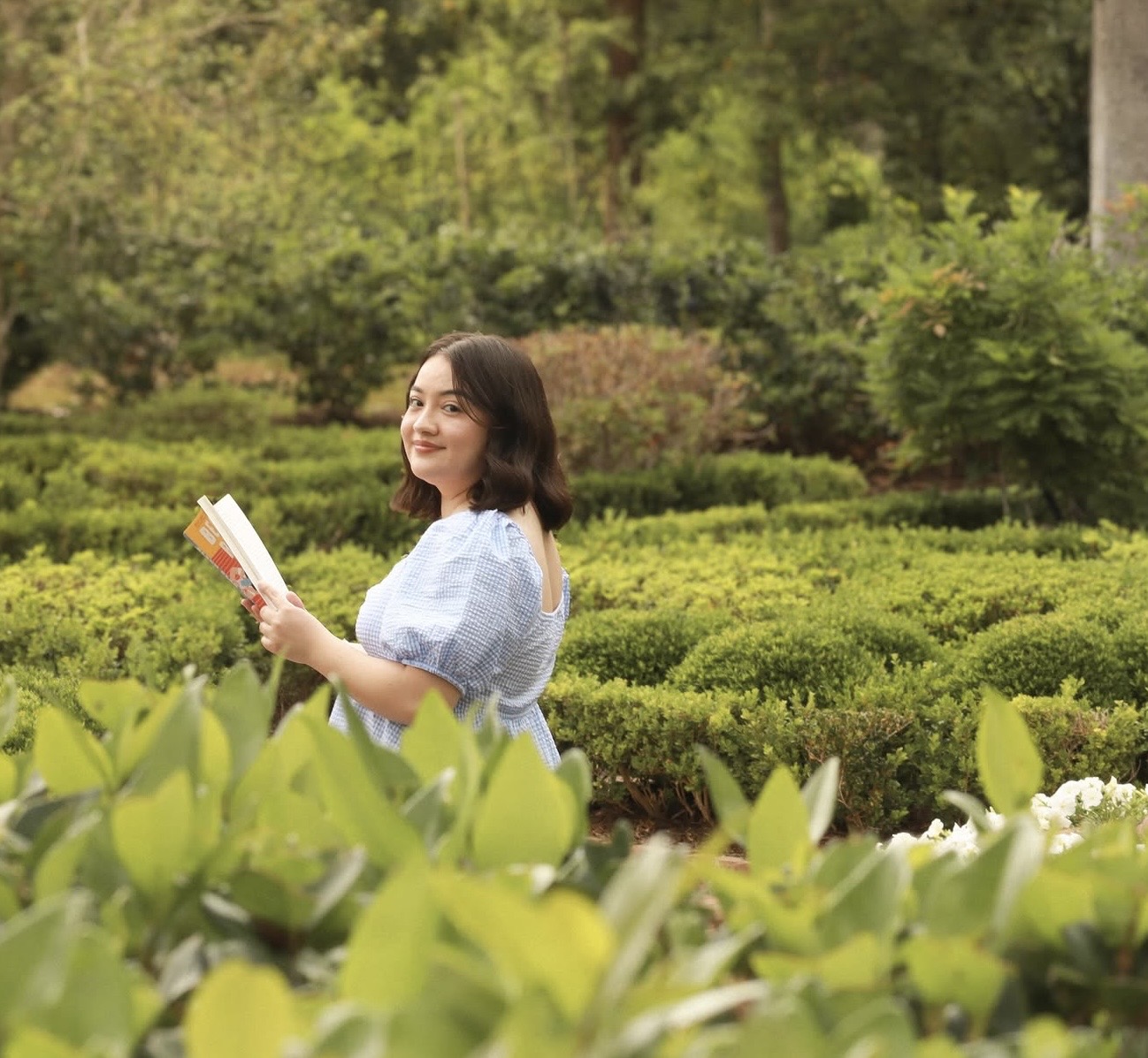 Jocelyne Roman holding a book in a green garden