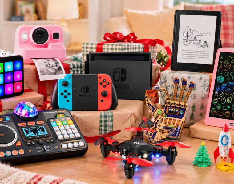 Tech gifts for kids under the Christmas tree, including a camera, Nintendo Switch, Kindle, drawing tablet, drone, and games