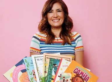 Naibe Reynoso holding children’s books for the Books, Media and Culture category