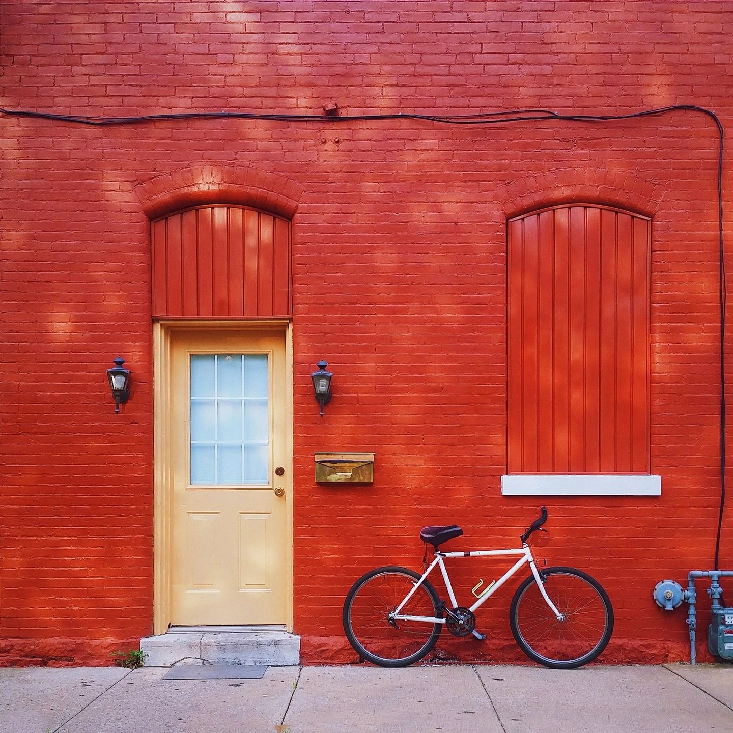 Striking red wall with orange bike and doll.